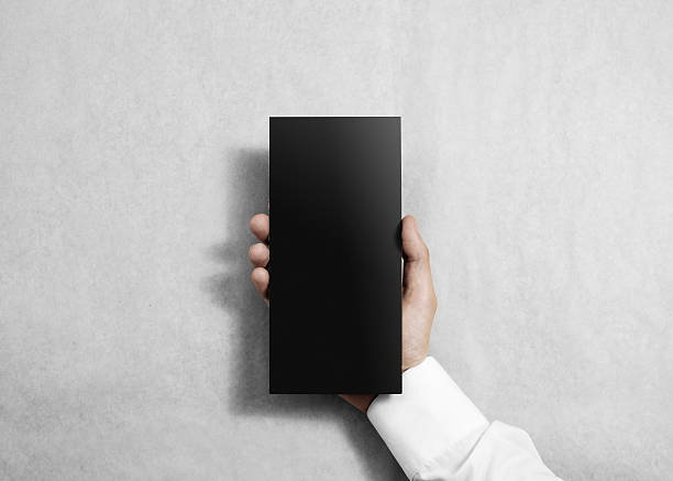 istock Hand holding blank black flyer brochure booklet in the hand. 537609416