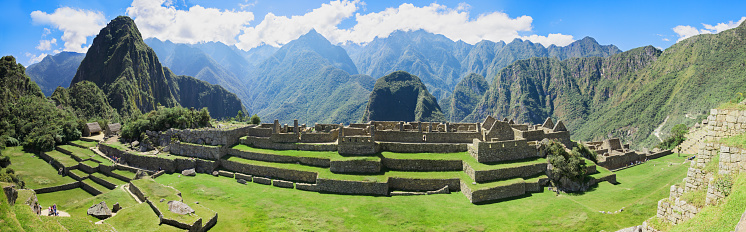 This captivating image showcases the iconic and well-preserved ruins of Machu Picchu, an Incan citadel set high in the Andes Mountains of Peru. The stone structures blend harmoniously with the lush greenery and the dramatic backdrop of steep cliffs, emphasizing the awe-inspiring craftsmanship of the Inca civilization