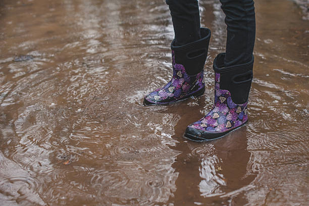 istock Child Wearing Rain Boots in Puddle 537611675