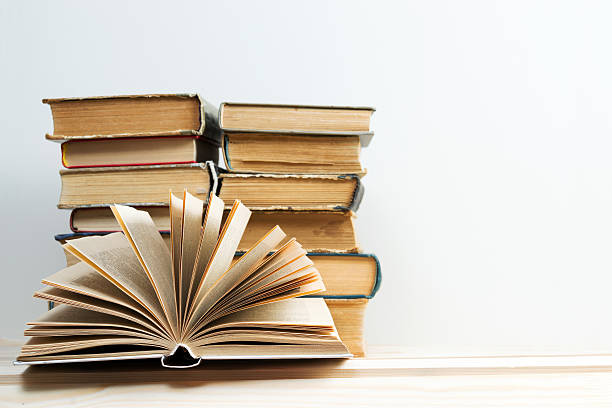 istock Open book, stack of hardback books on wooden table. Back 537612772