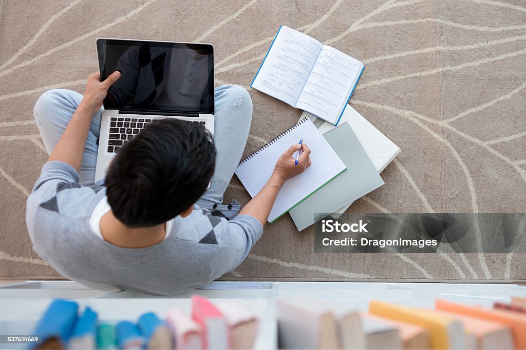 Doing homework Student sitting on the floor with a laptop and doing homework, view from above High Angle View Stock Photo