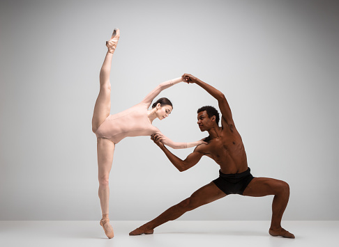 Couple of ballet dancers dancing over gray background