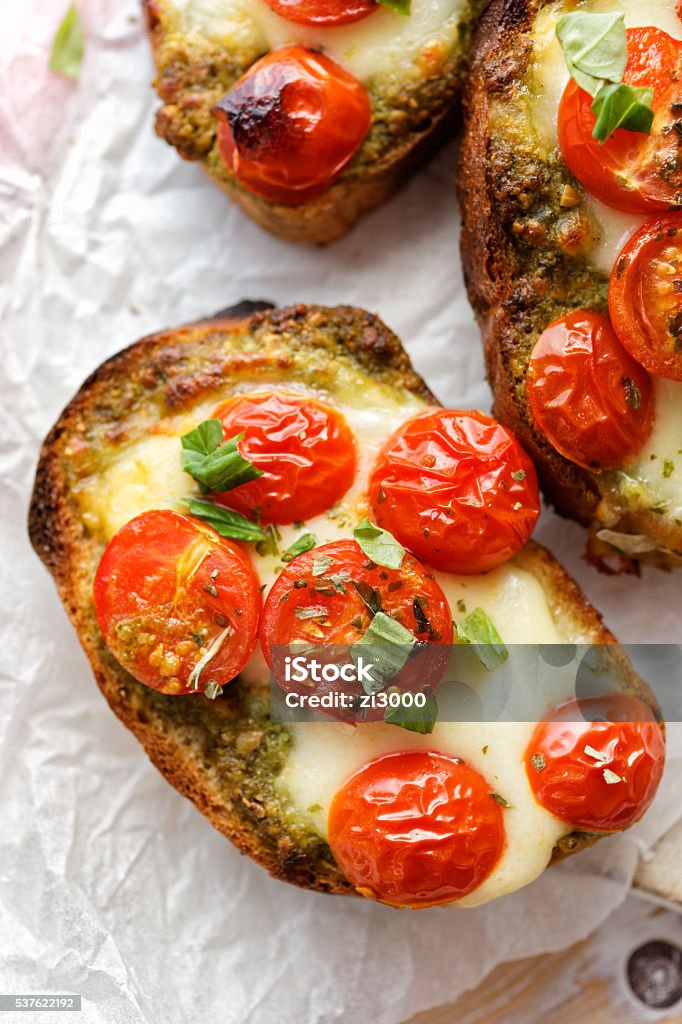 Bruschetta with cherry tomatoes, mozzarella cheese and herb pesto Vegetarian toast with cherry tomatoes, mozzarella cheese and herb pesto Antipasto Stock Photo