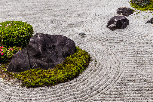 Japanese zen garden with yin yang stone in textured sand