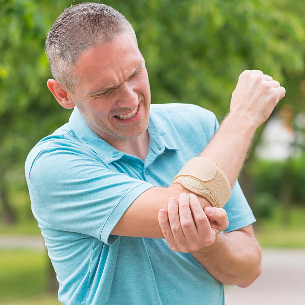 Man wearing elbow brace Man wearing elbow brace to reduce pain elbow photos stock pictures, royalty-free photos & images
