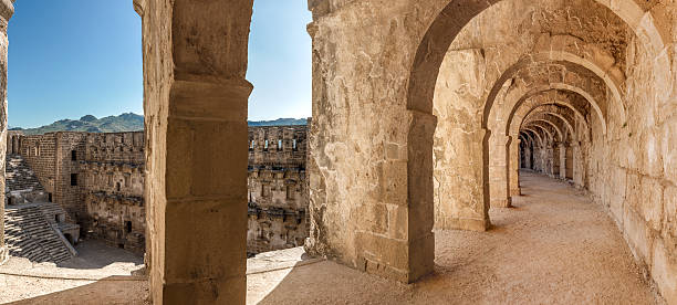 Arcade and amphitheater of Aspendos Panorama of top passageway in the theatre of Aspendos including arcade and a view of amphitheater and environs through space between columns. Aspendos amphitheater is remarkably well preserved part of ancient Pamphylian and later Greco-Roman city of Aspendos, now southern Turkey, Antalya province. ancient greece stock pictures, royalty-free photos & images