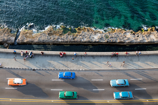 Vintage American cars speeding along the Malecon in Havana, Cuba, motion blur, Caribbean Sea is visible in the background, 50 megapixel image.