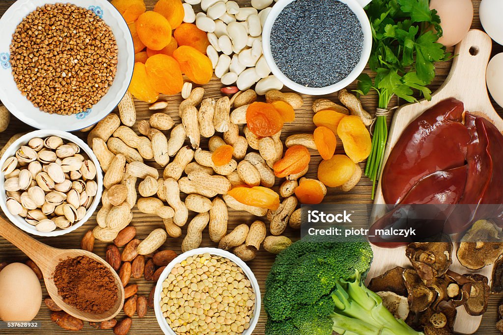 Iron rich foods Collection iron rich foods as liver, buckwheat, eggs, parsley leaves, dried apricots, cocoa, lentil, bean, blue poppy seed, broccoli, dried mushrooms, peanuts and pistachios on wooden table. Iron - Metal Stock Photo