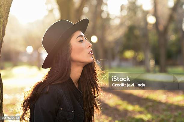 Thoughtful Woman Sitting Alone Outdoors Wearing Hat Stock Photo - Download Image Now