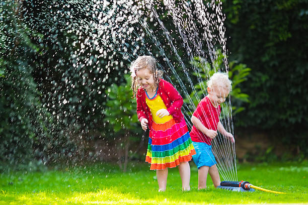 istock Kids playing with garden sprinkler 537630888
