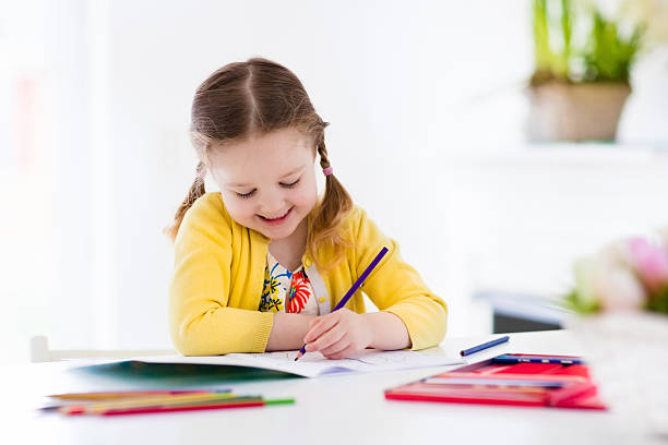 Little girl painting and writing Cute little girl doing homework, reading a book, coloring pages, writing and painting. Children paint. Kids draw. Preschooler with books at home. Preschoolers learn to write and read. Creative toddler left handed stock pictures, royalty-free photos & images