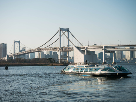 Tokyo, Japan - Mar 22, 2016 : The Tokyo Cruise boat named Hotaluna at Odaiba Seaside Park in Tokyo infront of the Rainbow bridge in the afternoon before sunset, Tokyo, Japan