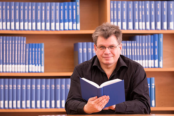 istock smiling mature man sitting in library 537665881
