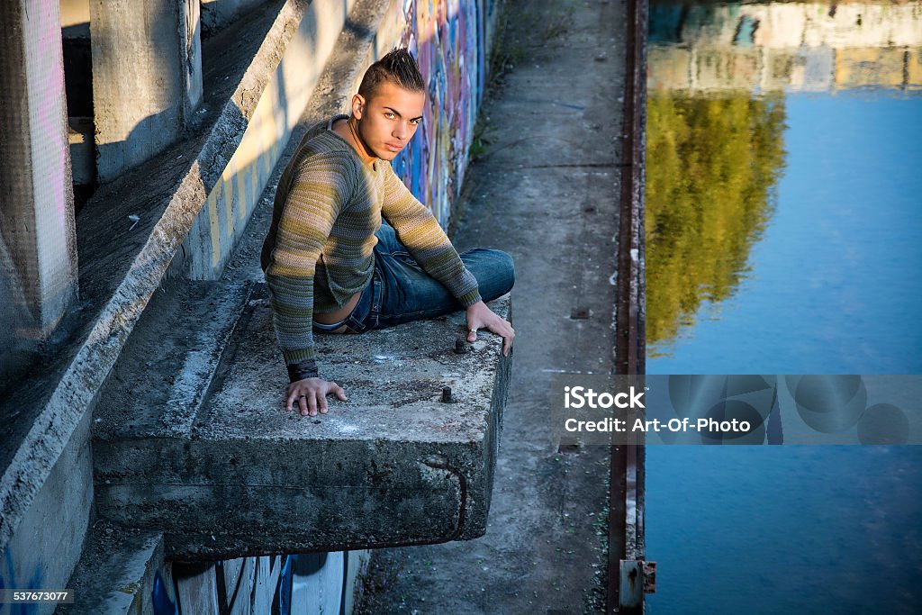 Handsome young man on concrete structure Handsome young man on concrete structure in abandoned industrial site 2015 Stock Photo