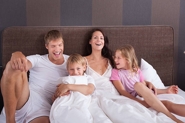 Family on vaccation in a hotel room bed stock photo