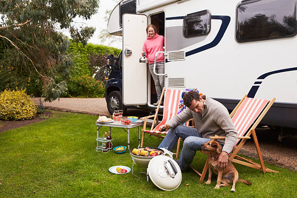 Couple In Van Enjoying Barbeque On Camping Holiday stock photo