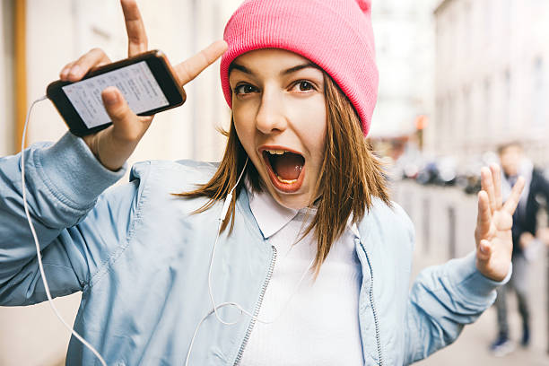 Teenager girl listening music Teenager girl listening music with headphones from a smart phone in the street of Paris, France 14 15 years photos stock pictures, royalty-free photos & images