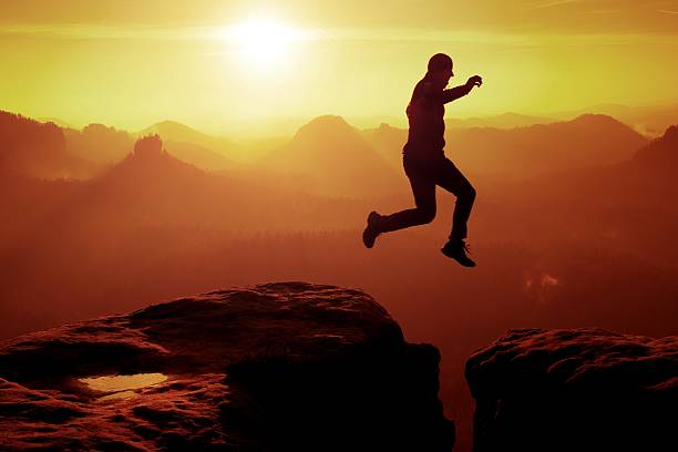 istock Young crazy man jump on mountain peak. Jumping man silhouette 537686884