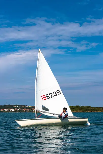 Photo of Young man sails a laser olympic  class sailing boat