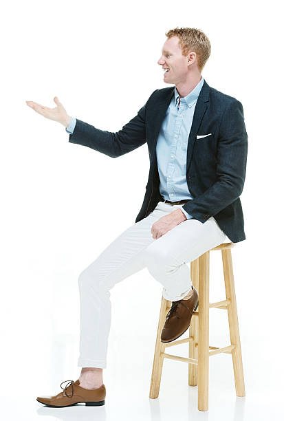 istock Smiling fashionable man on stool presenting 537697811