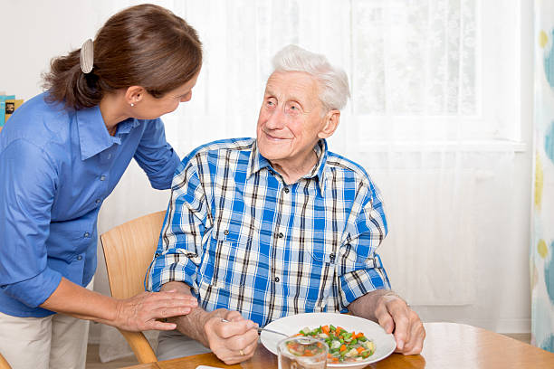 Caregiver with senior man, helping eating