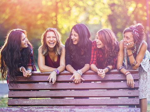 Teenage girls talking and smiling outdoors in the summer