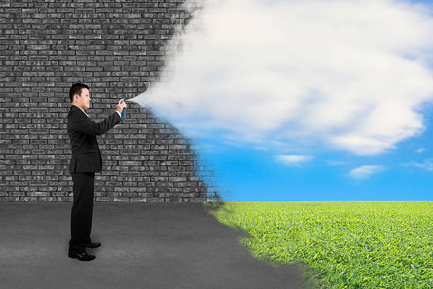 istock Businessman spraying clouds sky grass paint cover old brick wall 537700609