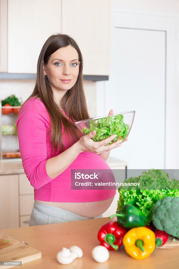Pregnant woman making a salad and smiling 20-29 Years Stock Photo