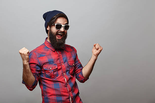 Lucky young hipster man isolated over grey background