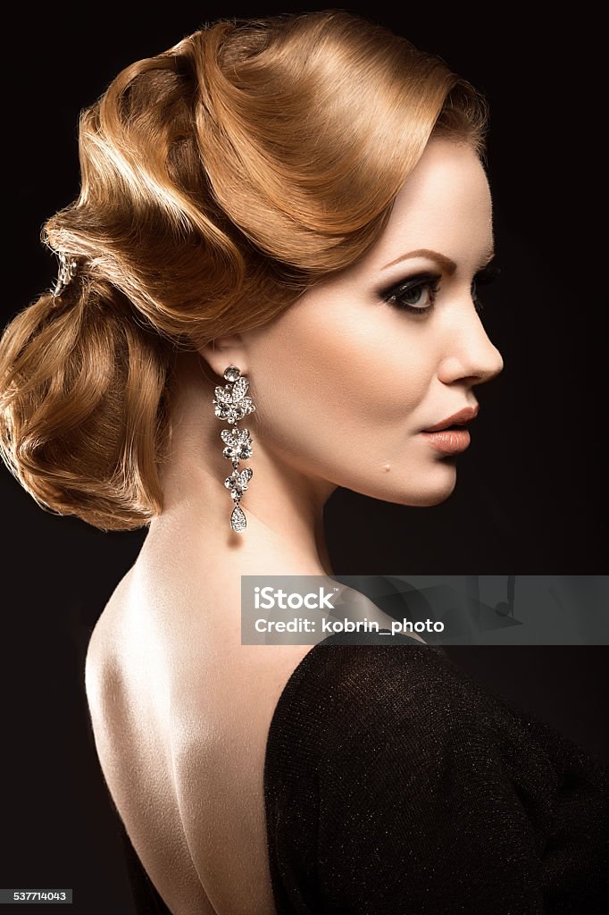 Beautiful red-haired girl in black dress with smooth evening haircut Beautiful red-haired girl in a black dress with a smooth evening haircut in the form of waves and bright makeup. Beauty face. Picture taken in the studio on a black background. Black Background Stock Photo