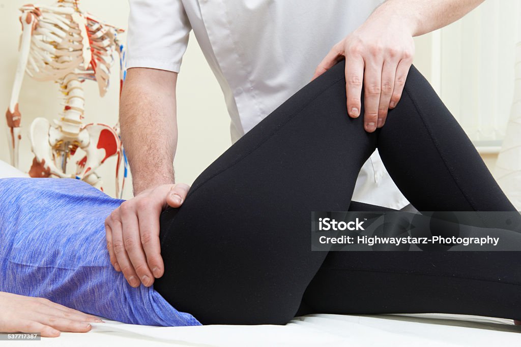 Male Osteopath Treating Female Patient With Hip Problem Hip - Body Part Stock Photo