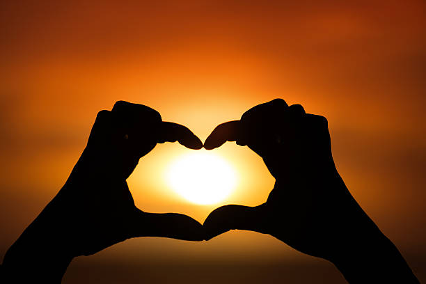 istock Silhouette of hand in heart shape with sun down 537725338
