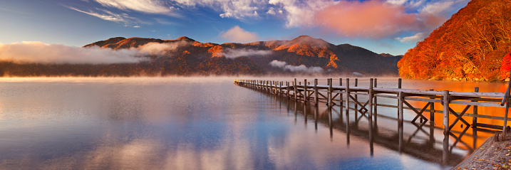 The Monte Rosa peaks are reflected the lake called Blue Lake, on a sunny, crystal-clear autumn morning. The larch trees have already changed their colors to warmer autumn hues.