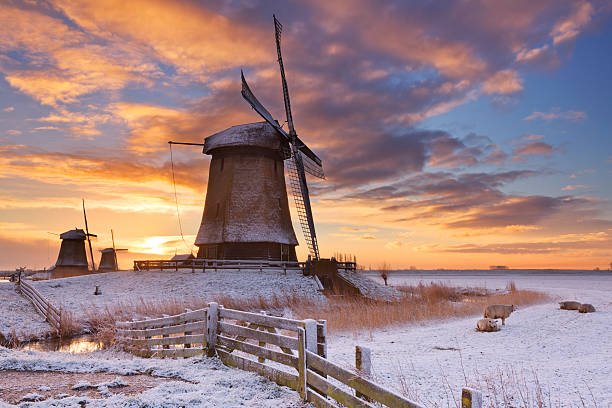 moulins à vent néerlandais traditionnels en hiver au lever du soleil - polder windmill space landscape photos et images de collection