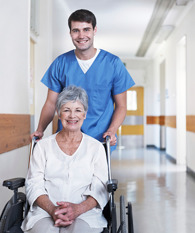 Shot of a young male nurse pushing an elderly patient in a wheelchair