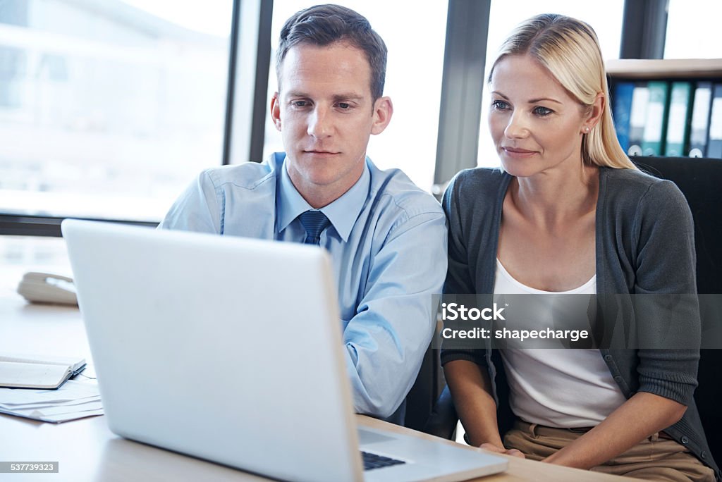 Let's see what happens Shot of two business people working together on a laptop 2015 Stock Photo