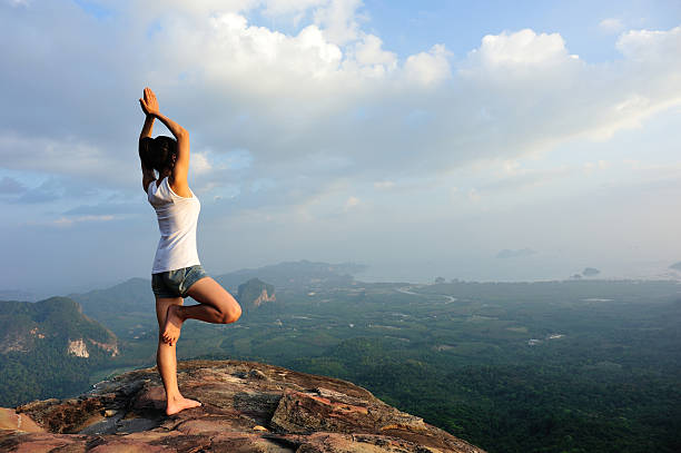 istock woman mountain peak cliff practice yoga 537741331