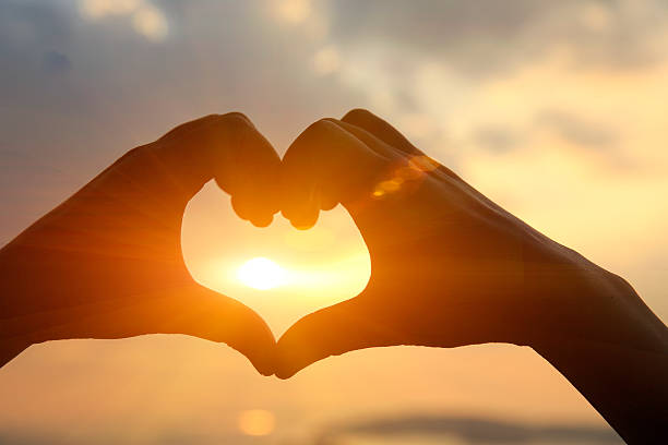 istock hands make a heart shape against sunset at seaside 537761051