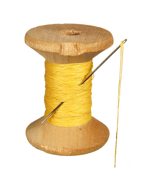 istock Old wooden spool of yellow thread and needle . 537761289