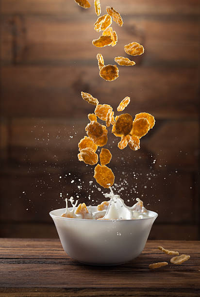 Falling breakfast flakes with milk splash on wood