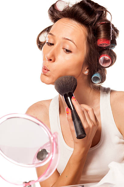 istock Happy housewife with curlers applying makeup on her face 537766239