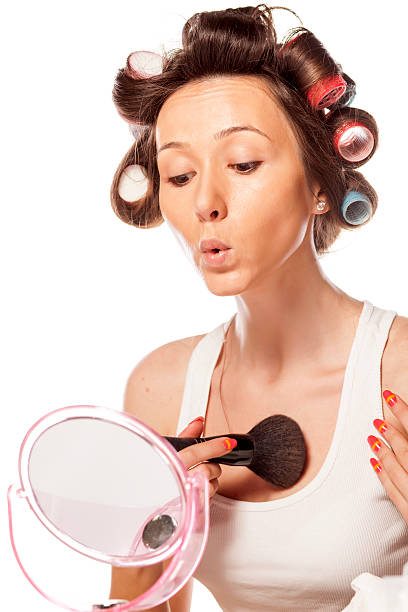 happy hausfrau mit lockenwickler anwenden make-up auf ihr dekolleté - fashion model women cleavage human hair stock-fotos und bilder
