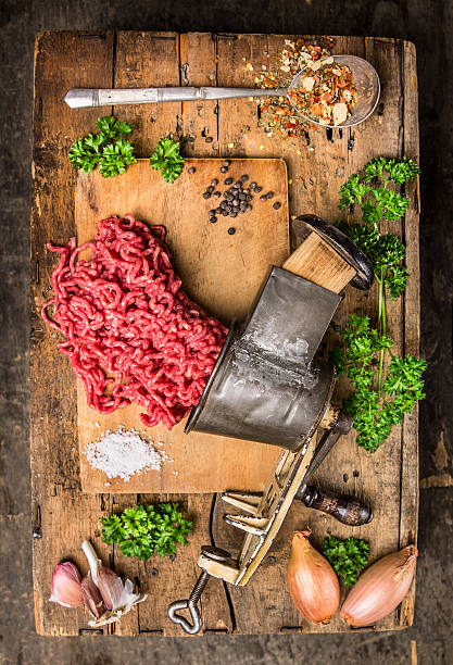 mincemeat de vintage máquina de picar carne na mesa de madeira com plantas aromáticas - meat grinder ground beef meat imagens e fotografias de stock