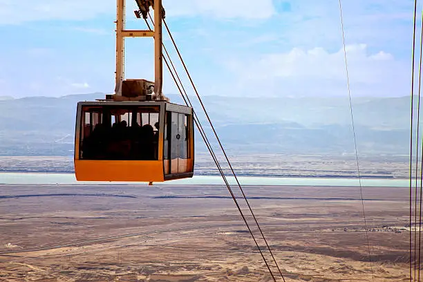 Cable car approaching against a view of Dead sea and Jordan Mountains (sunrise lighting)