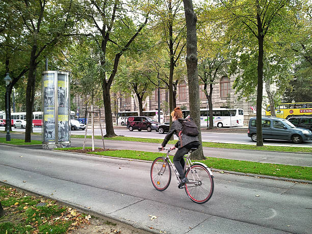 Vienna, Austria - September 25, 2014: Young woman riding a bicycle on the Burgring Street in the center of city.