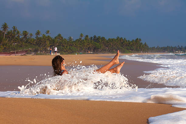 Girl is sitting on the beach and wave stock photo