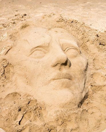 Stock photo showing close-up view of a complex sandcastle built on a sunny, golden sandy beach. Summer holiday, tourism and activities concept.