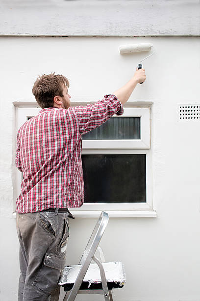 istock Man painting house wall, stepladder and roller. DIY Home Improvement. 537806102