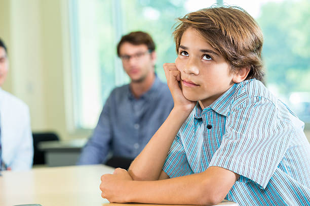 Boy annoyed with parents Boy rolling his eyes at his parents. He is turned away from them. rolling eyes irritation displeased facial expression stock pictures, royalty-free photos & images