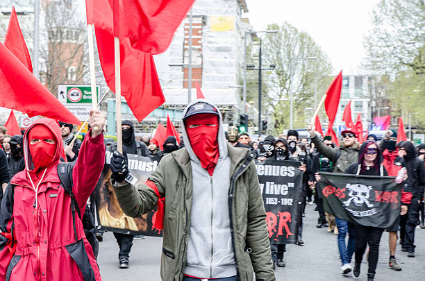 London, England - May 1, 2016: Large group of young adult marching with a streamer in the street during day of springtime.